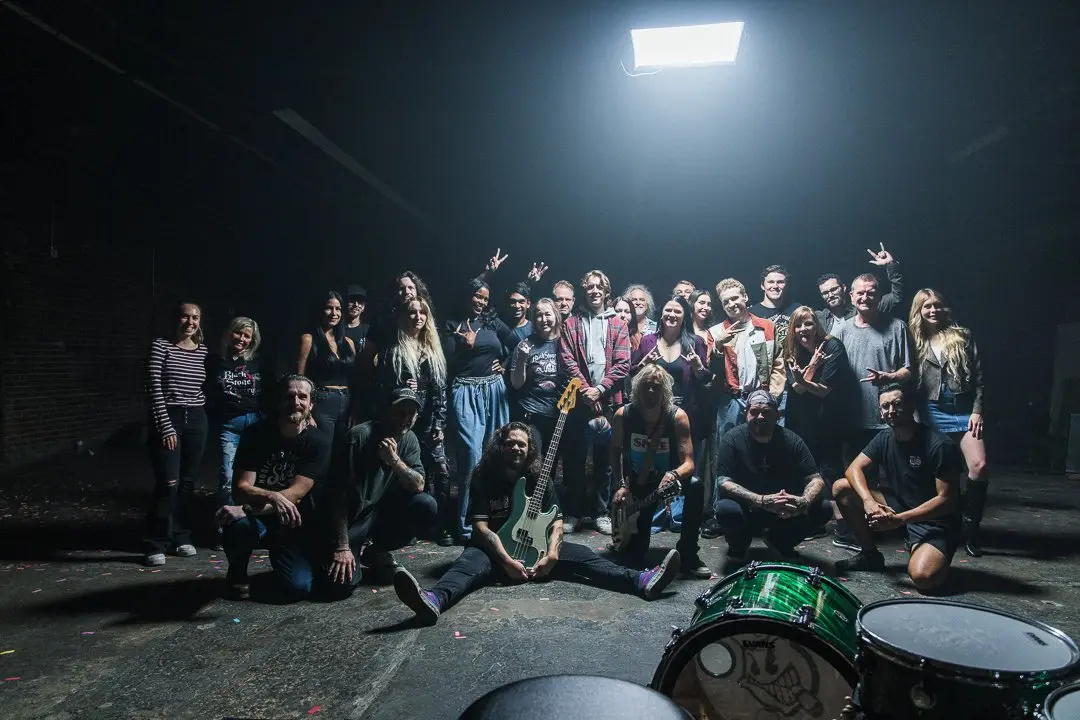 The full crew and cast on a dark music-video set