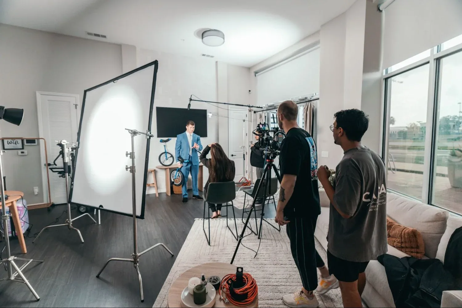 Camera, diffusion frame, and crew set for an on-location interview inside an apartment